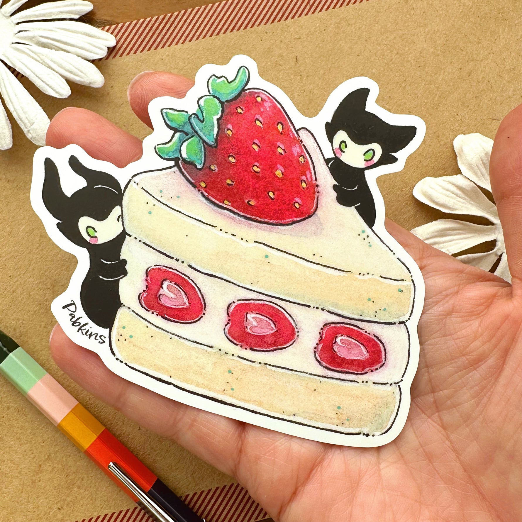 Strawberry cake spirits sticker held in a hand